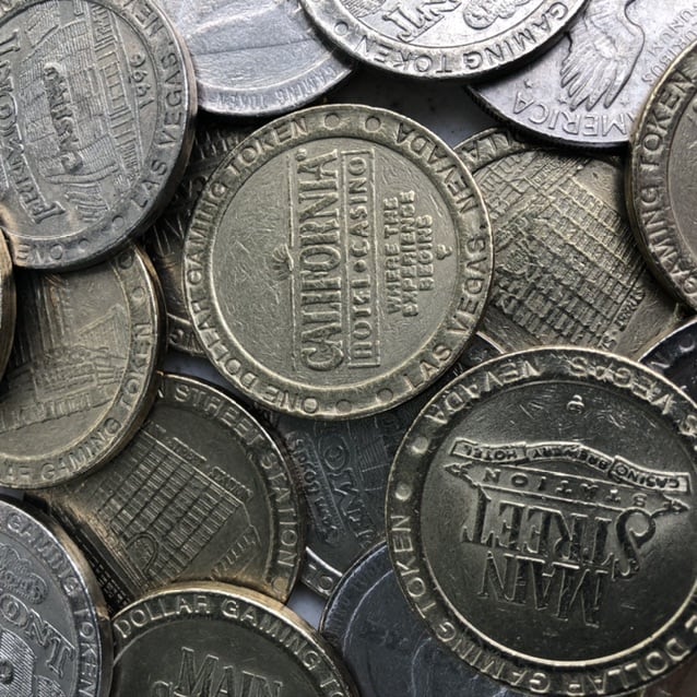 Pile of metal slot tokens from various Las Vegas casinos