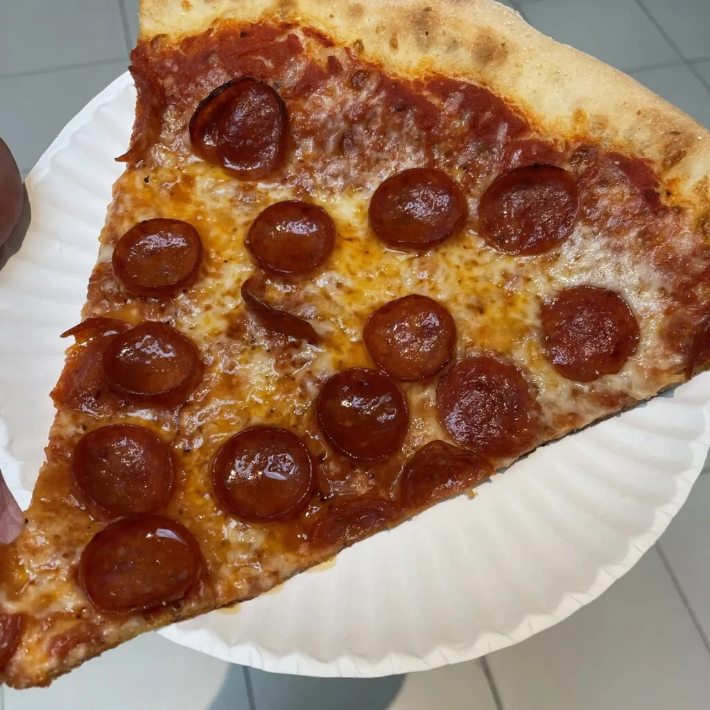 Slice of greasy pepperoni pizza