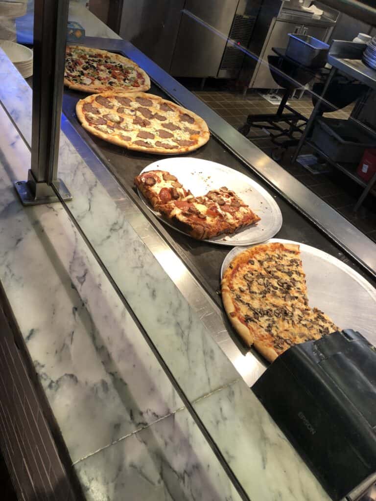 4 pizzas sitting on a counter at Secret Pizza