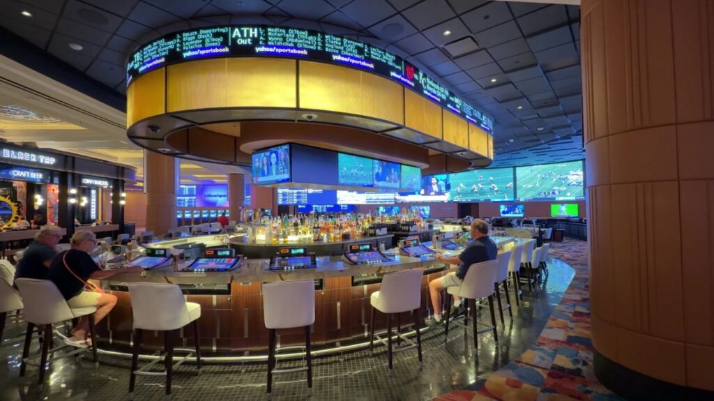 An oval shaped bar with an overhead video board in the book.