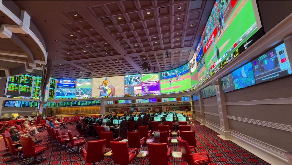 An army of red chairs point at the overhead, curved video board in the sportsbook. 