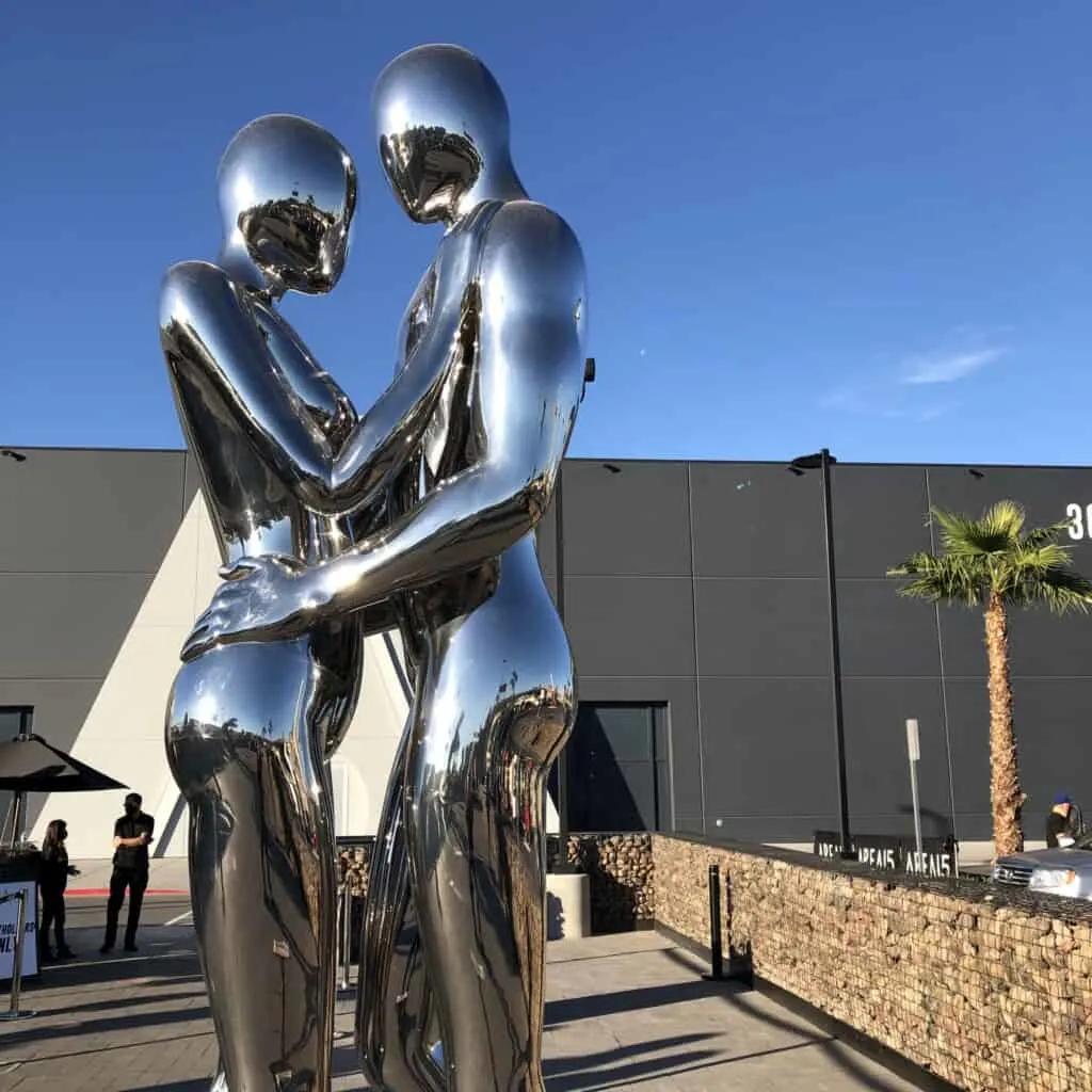 Chrome statue depicting 2 people embracing outdoors at Area15