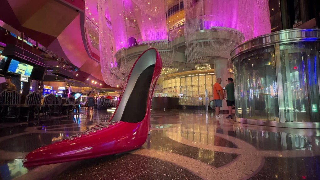A giant red women's shoe sits as a photo op with the Chandelier Bar illuminated in purple behind it.