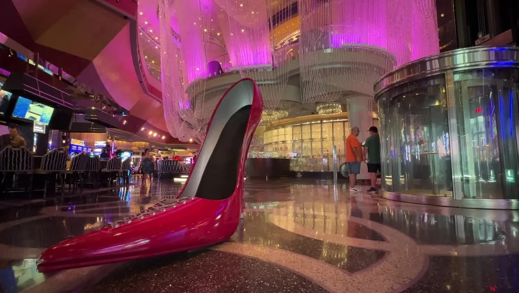 A giant red women's shoe sits as a photo op with the Chandelier Bar illuminated in purple behind it.