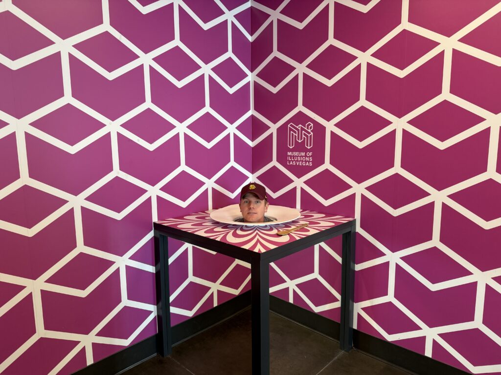 An illusion that makes it appear as if my head is on a platter atop a table.
