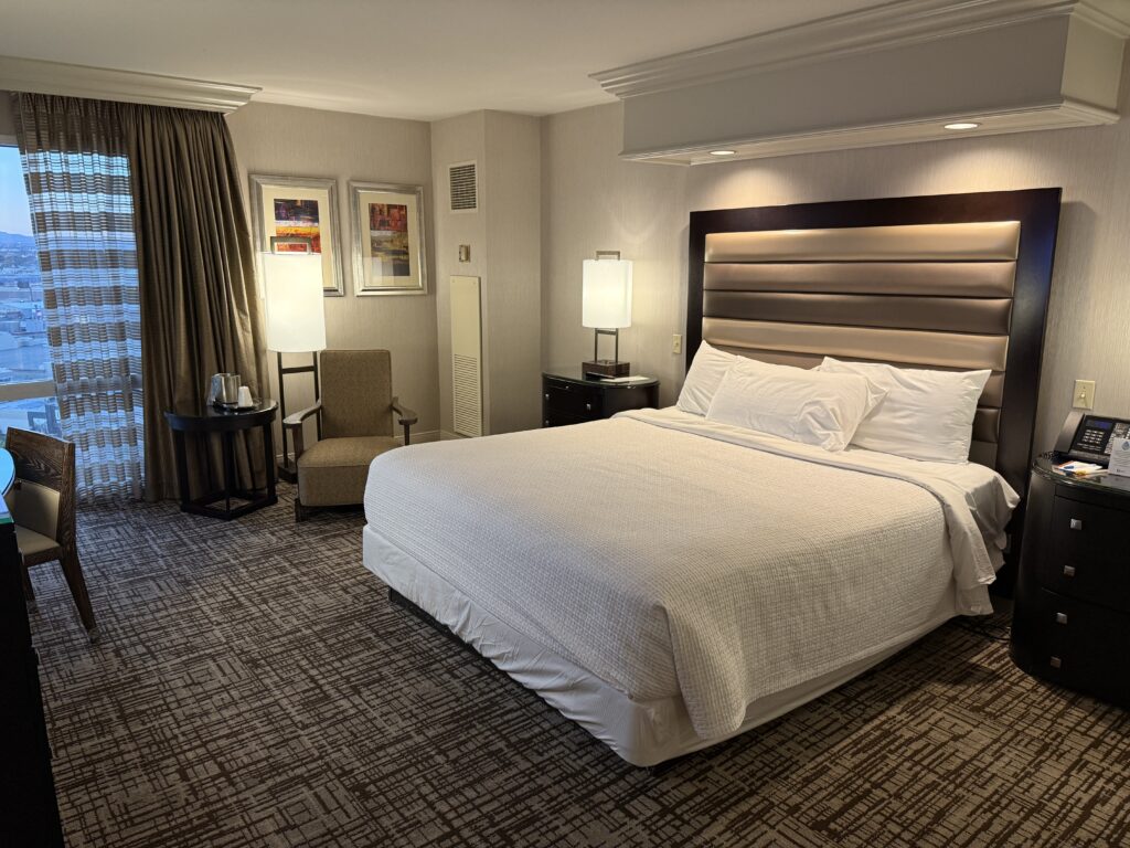 A king bed, illuminated from above, with a padded headboard.