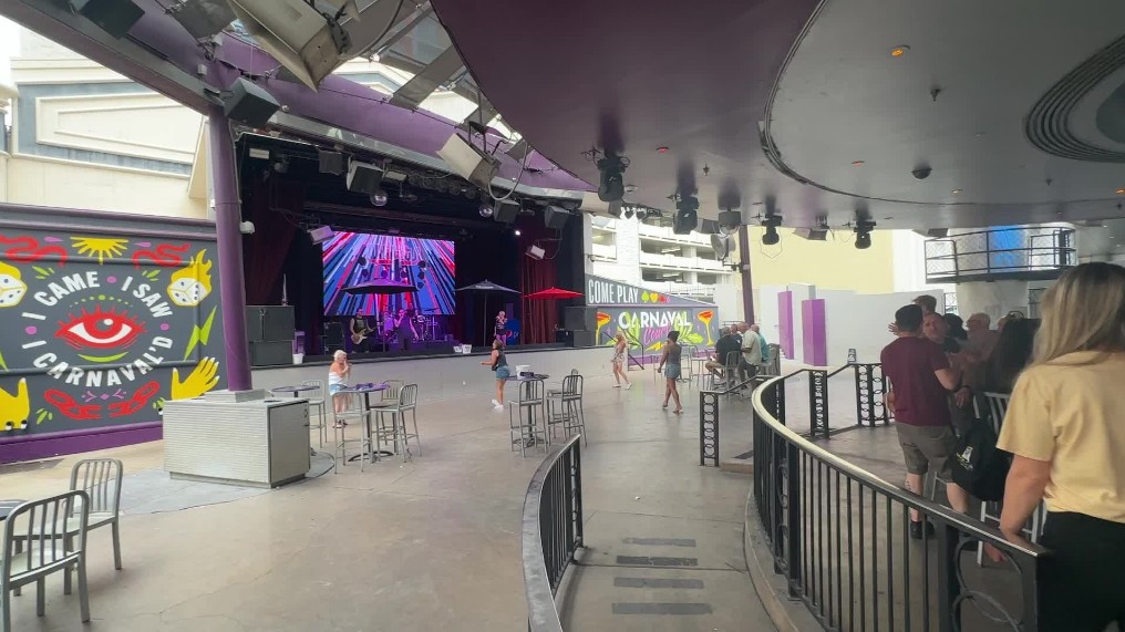 A band on stage at Carnaval Court, with 2 individual people dancing.