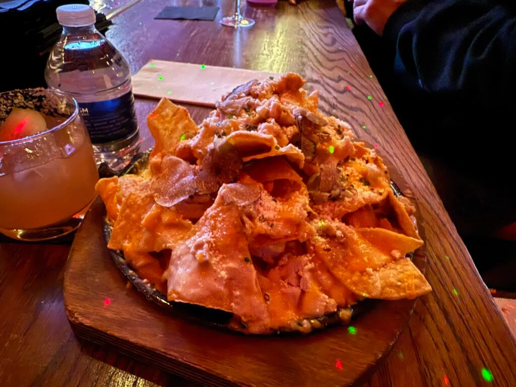 A plate piled with nachos on the bartop. 