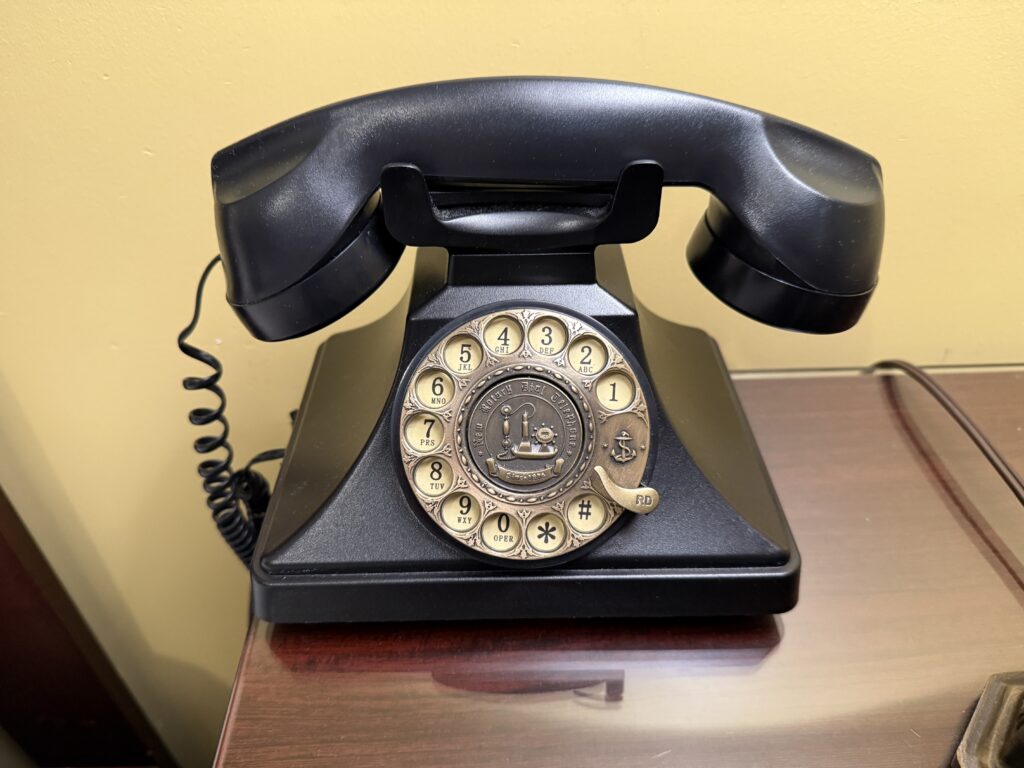 An old timey rotary phone on the end table. 