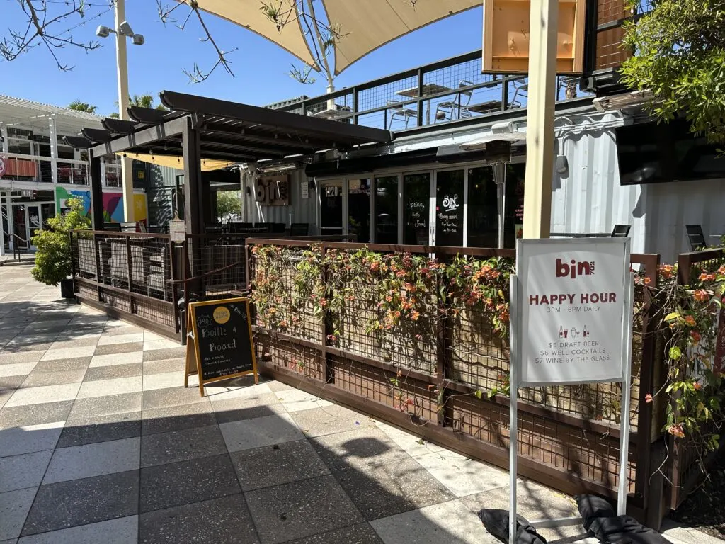 Bin702's outdoor seating patio surrounded by a fence with green vines growing on it.