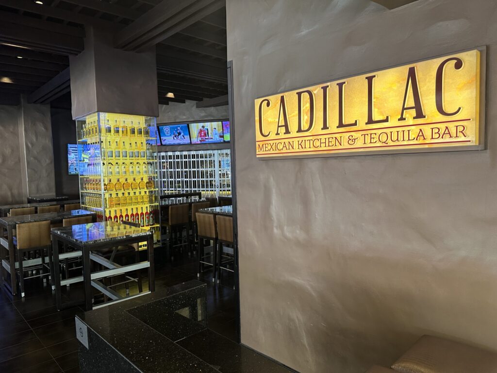 Exterior of Cadillac Mexican Kitchen. Inside, you can see a pillar surrounded by illuminated bottles of liquor.