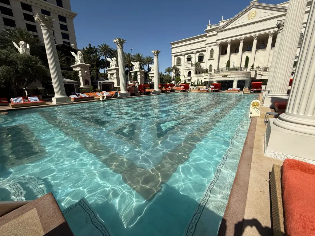 A large rectangular pool with a roman building in the background.