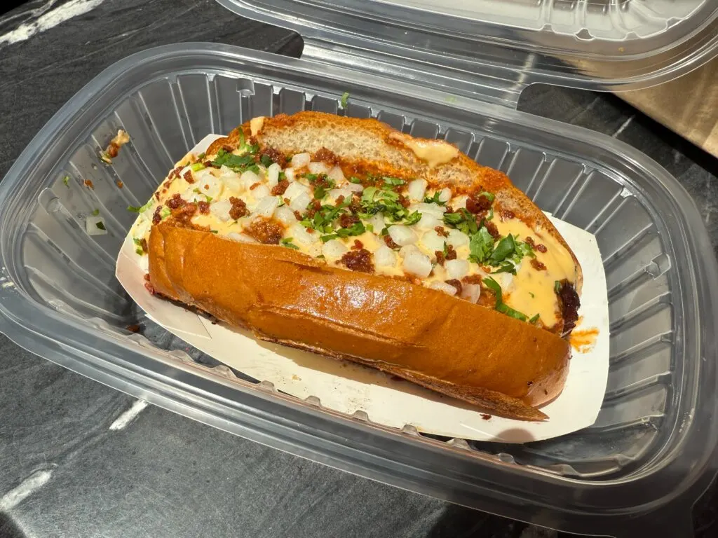 A substantial chili dog in a clear tray.