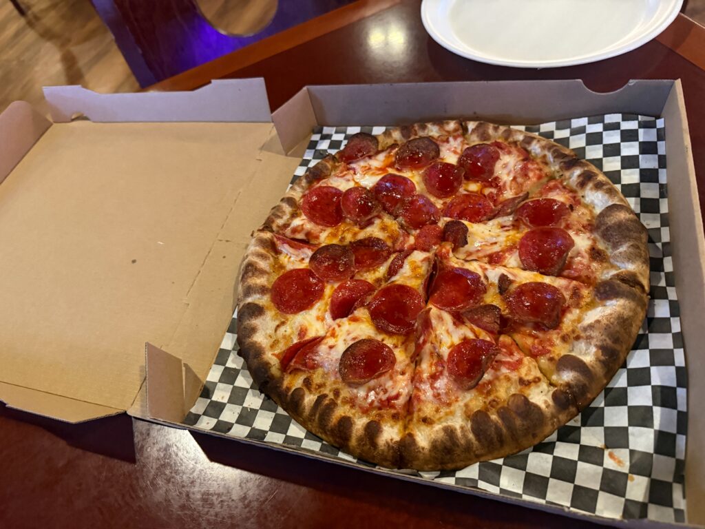 A whole pepperoni pizza in a pizza box on a table. 