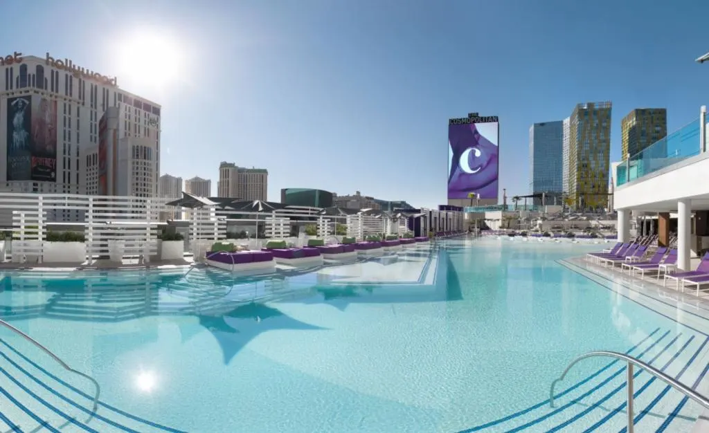 Cosmopolitan's Boulevard Pool with no people in it, surrounded by purple loungers and daybeds. 