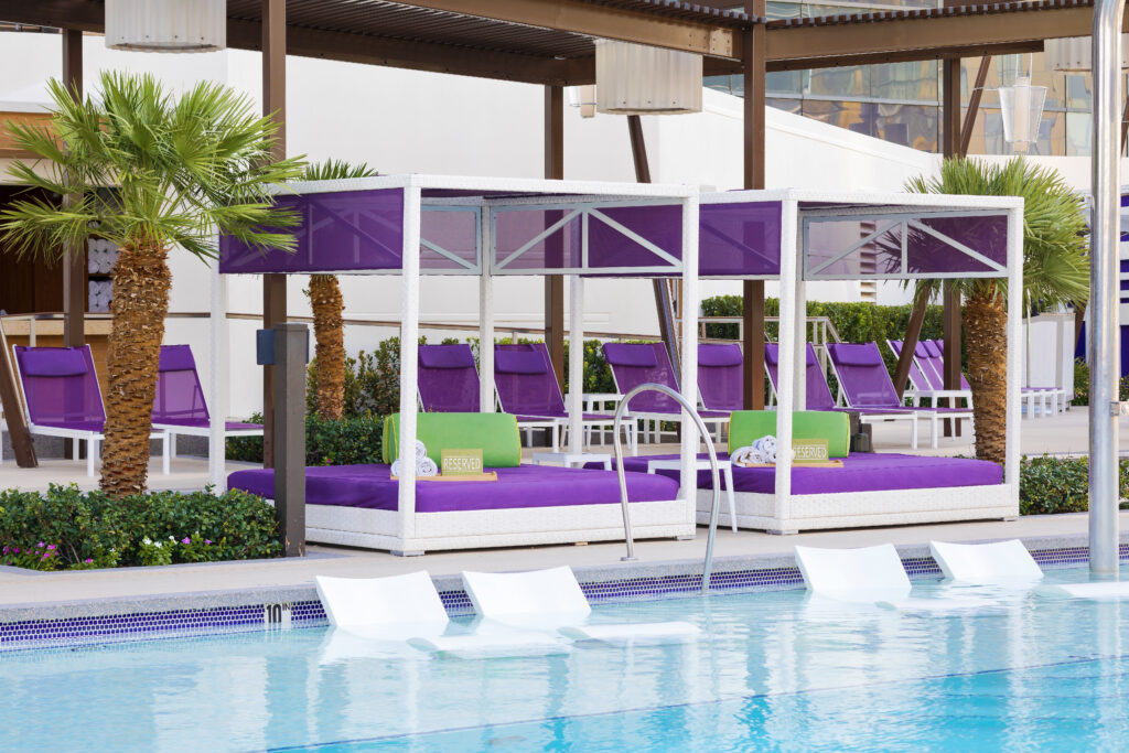 Chelsea Pool with partially submerged loungers. In the background is a cabana with purple accents. 