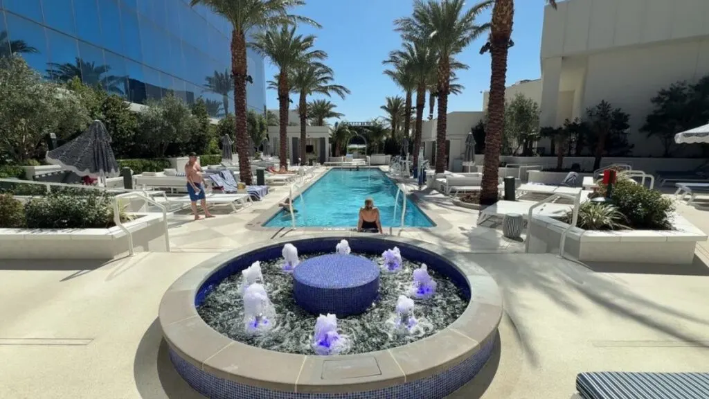 An illuminated decorative fountain in front of a long rectangular pool that extends into the distance. 