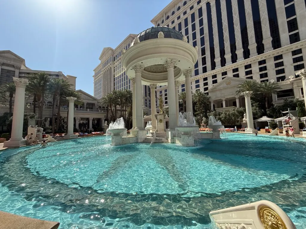 A pool with a roman column in the middle of it. 