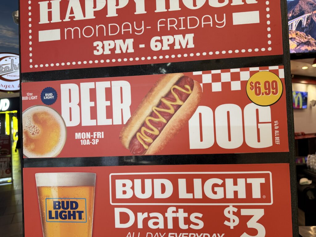 A sign advertising Ketchup's beer and a dog deal.