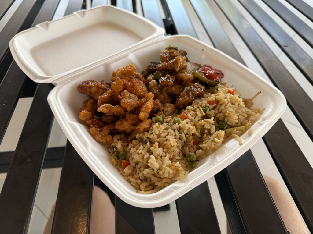 A styrofaom container with 2 types of chicen and fried rice in it. 