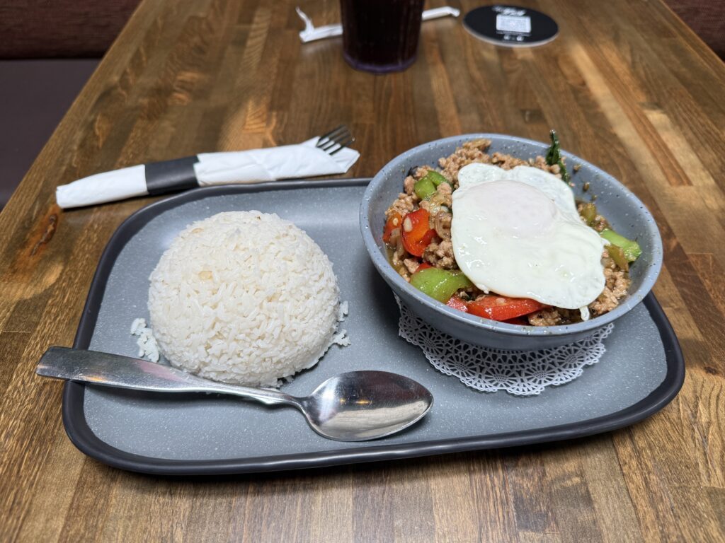 A tray with a big ball of white rice to the left, and a bowl of ground pork topped with veggies and an over-easy egg atop it to the right. 