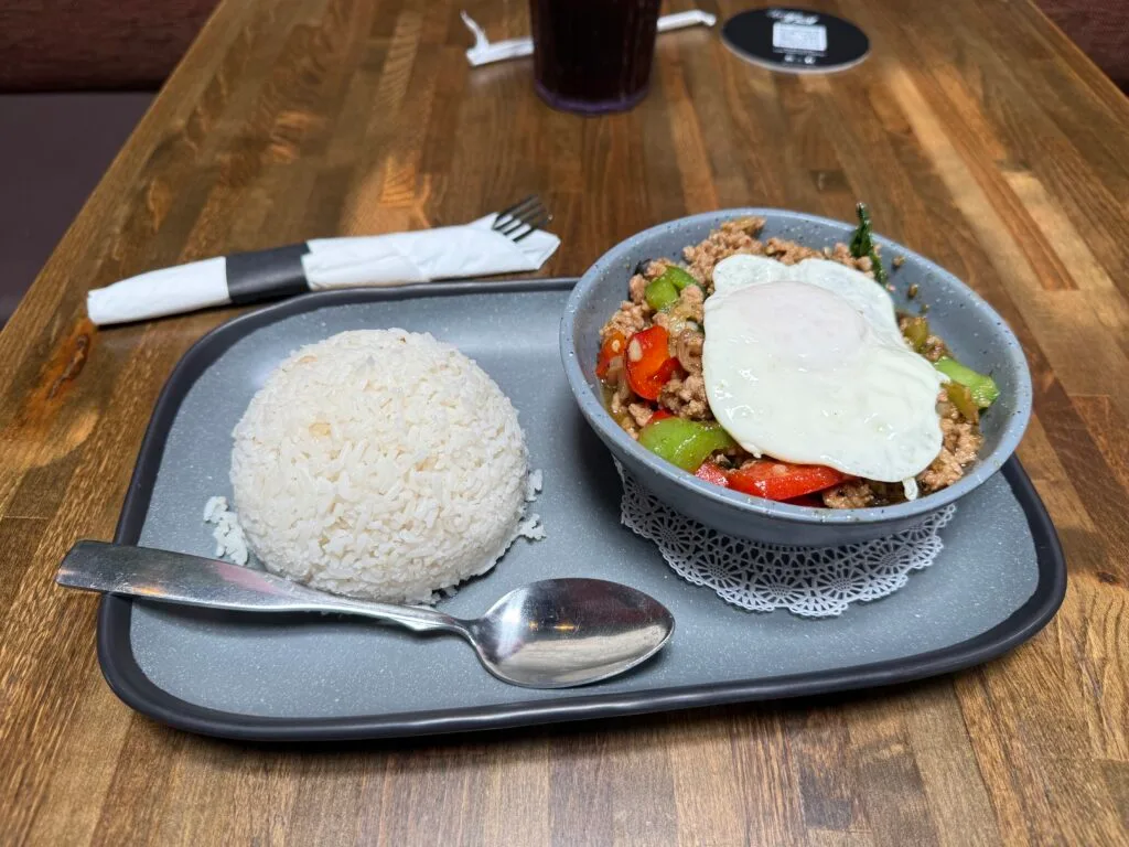 A tray with a big ball of white rice to the left, and a bowl of ground pork topped with veggies and an over-easy egg atop it to the right. 