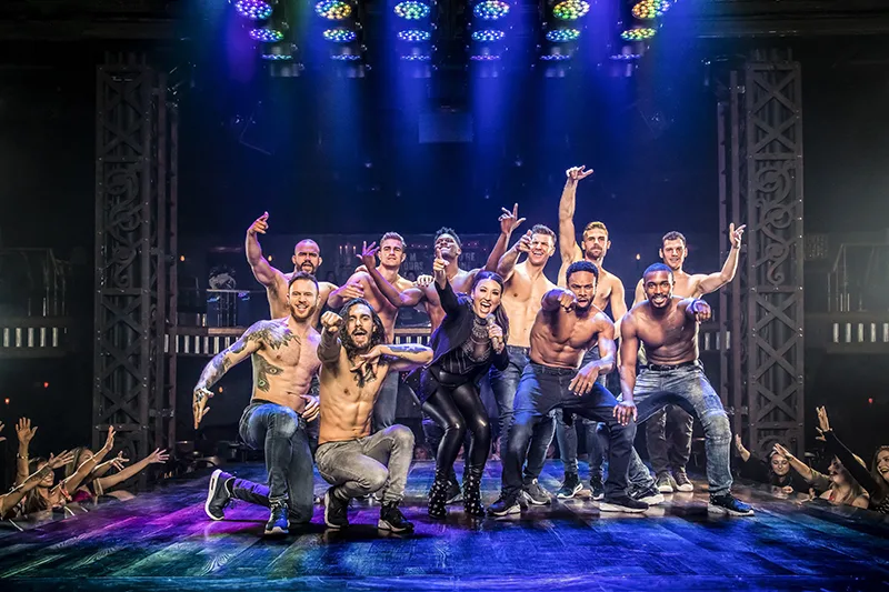 Performers of Magic MIke LIve pose shirtless together on stage