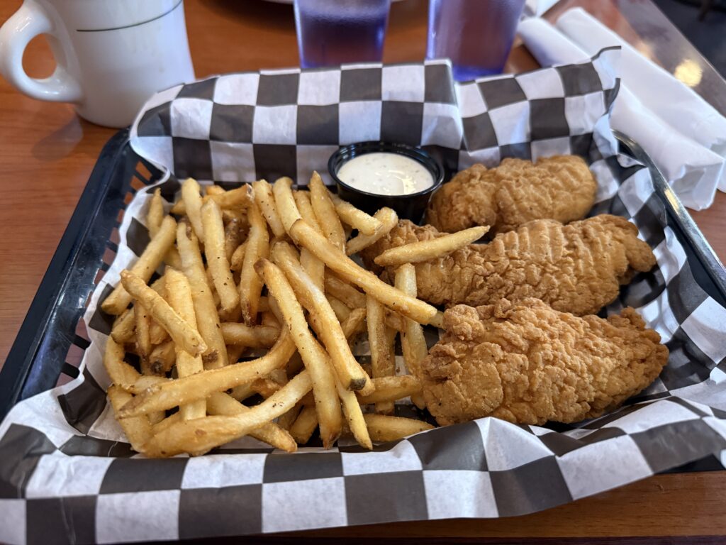 A basket of chicken fingers and french fries.