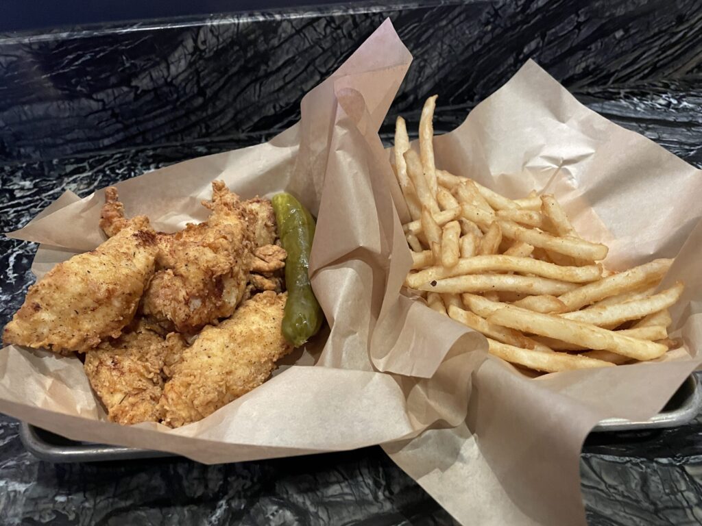 A basket of chicken tenders next to a basket of fries ordered from Snacks at Bellagio.