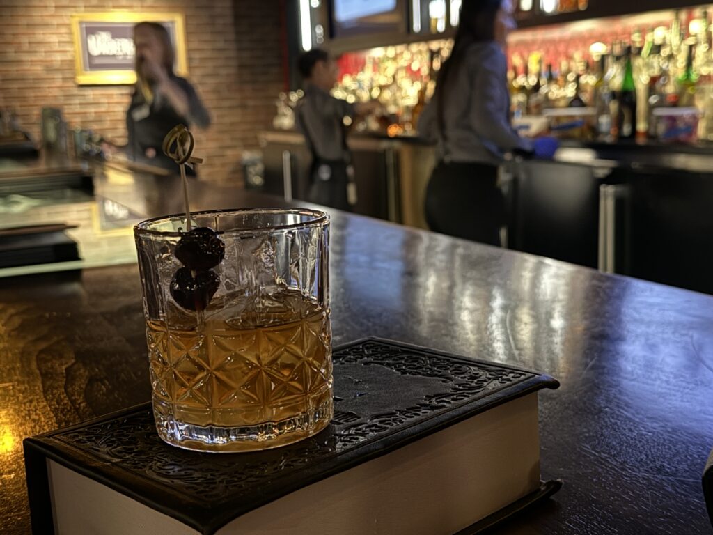 An old fashioned in a glass sits atop a closed book.