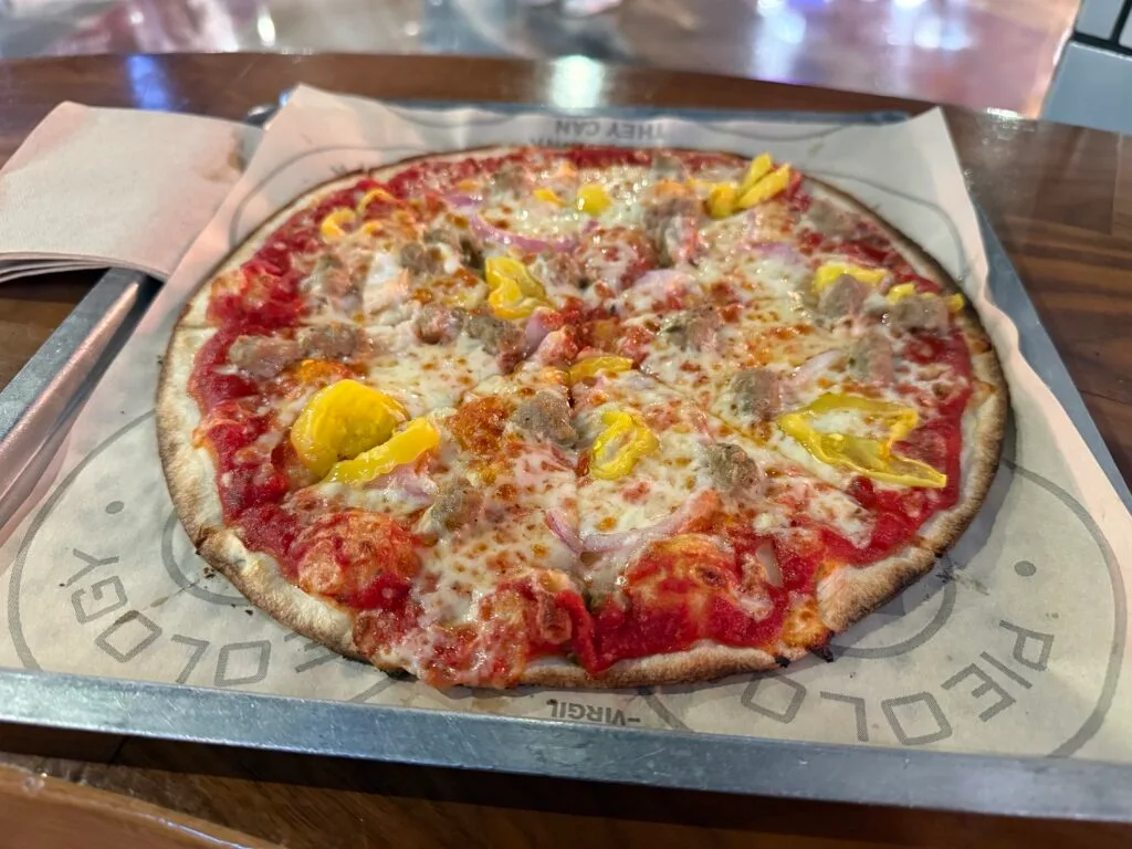 An 11 inch persoal pizza with sausage and bananna peppers atop it.