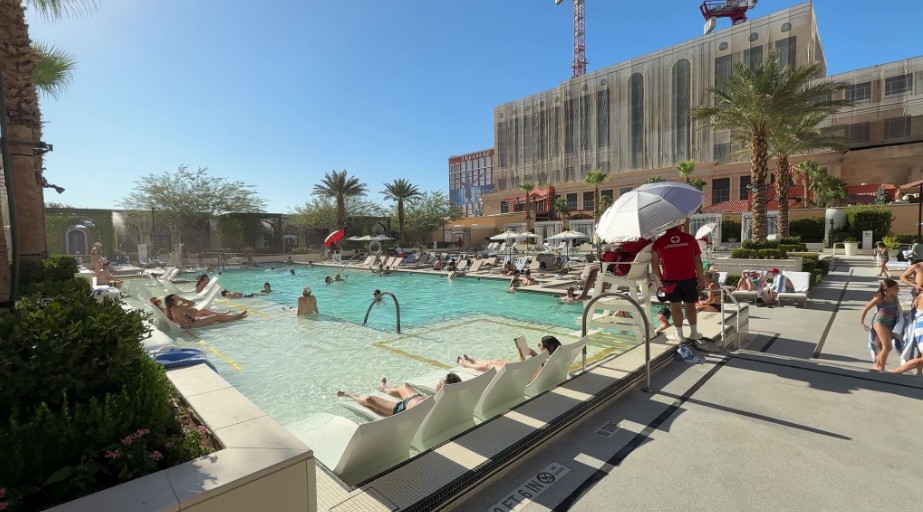 A pool at The Venetian, with a shallow area for seating and the St. Regis Tower in the background .