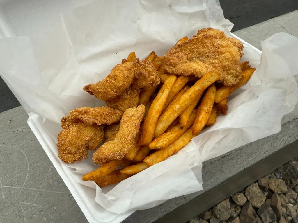 5 meaty, fried shrimp sit atop a basket of french fries. 