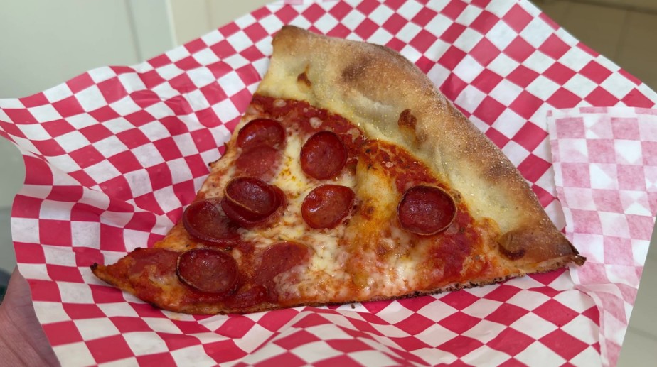 A slice of pepperoni pizza on a checkered paper plate.