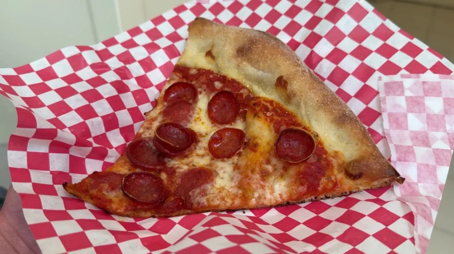 A slice of pepperoni pizza on a checkered paper plate. 