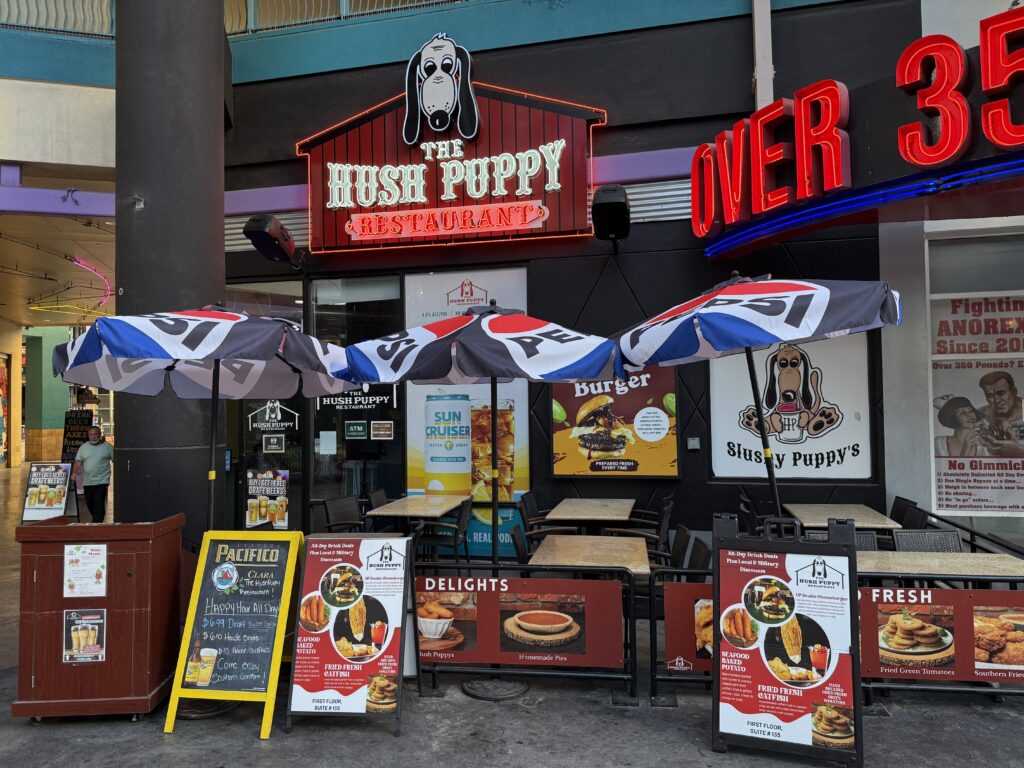 Exterior of The Hush Puppy, with an abudance of promotional signage and outdoor seating. 