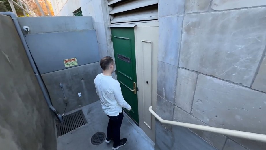A green door at the bottom of the staircase that is the entrance to the speakeasy.