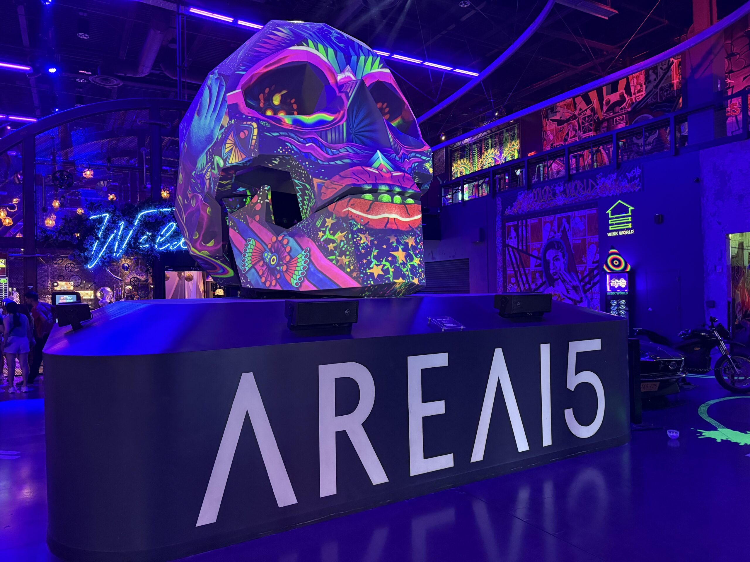 Vibrant neon-lit arcade interior with a giant colorful graffiti-covered sculpture as the centerpiece.