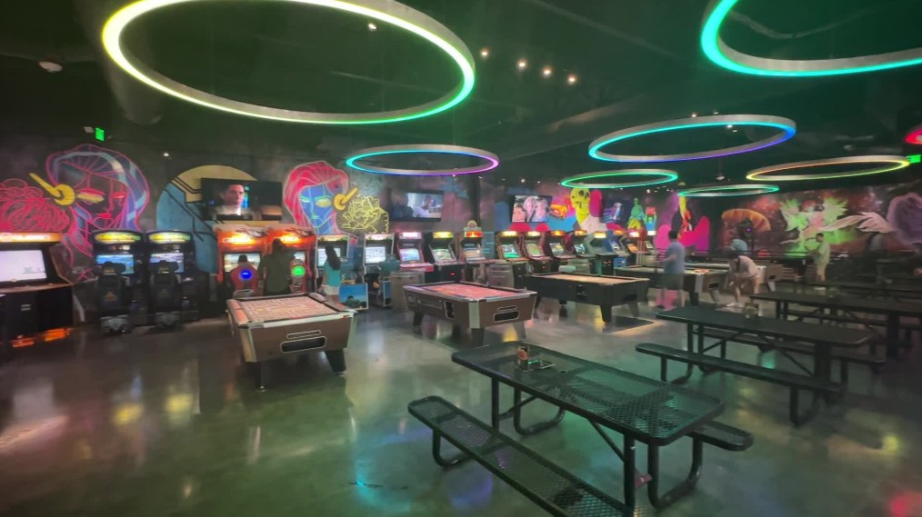 Pool tables in the middle of the room, surrounded by vintage arcade games lining the walls.