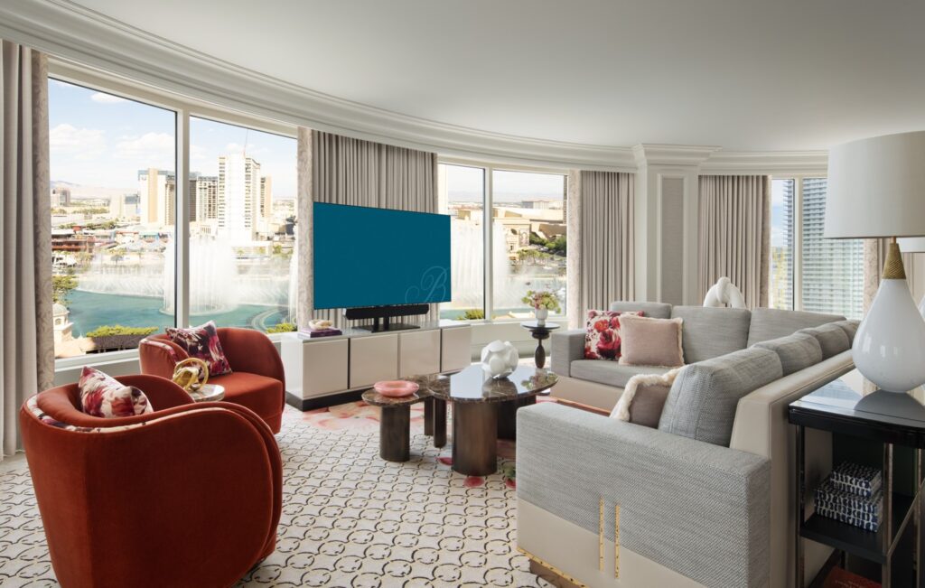 A large living area with seating pointed at a TV and windows overlooking the iconic fountains.