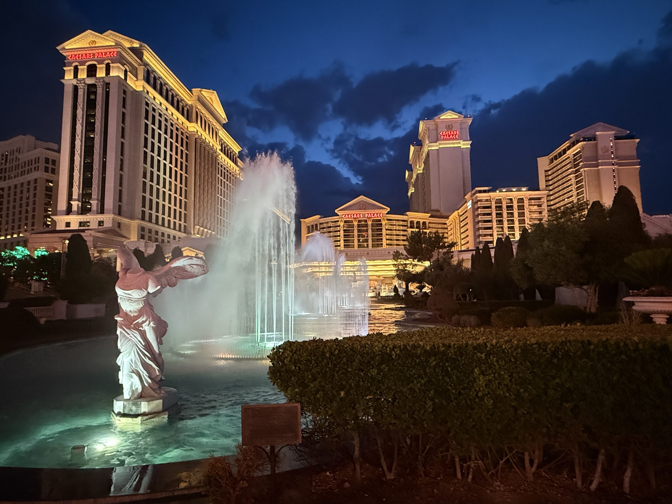 Exterior of Caesars at night, with the fountains in the foreground illuminated.