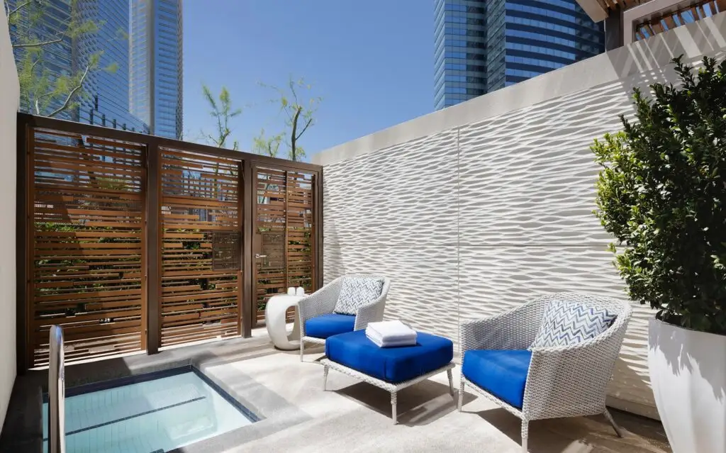 The outdoor patio, which is surrounded by privacy walls, with 2 chairs and a small square dipping pool. 