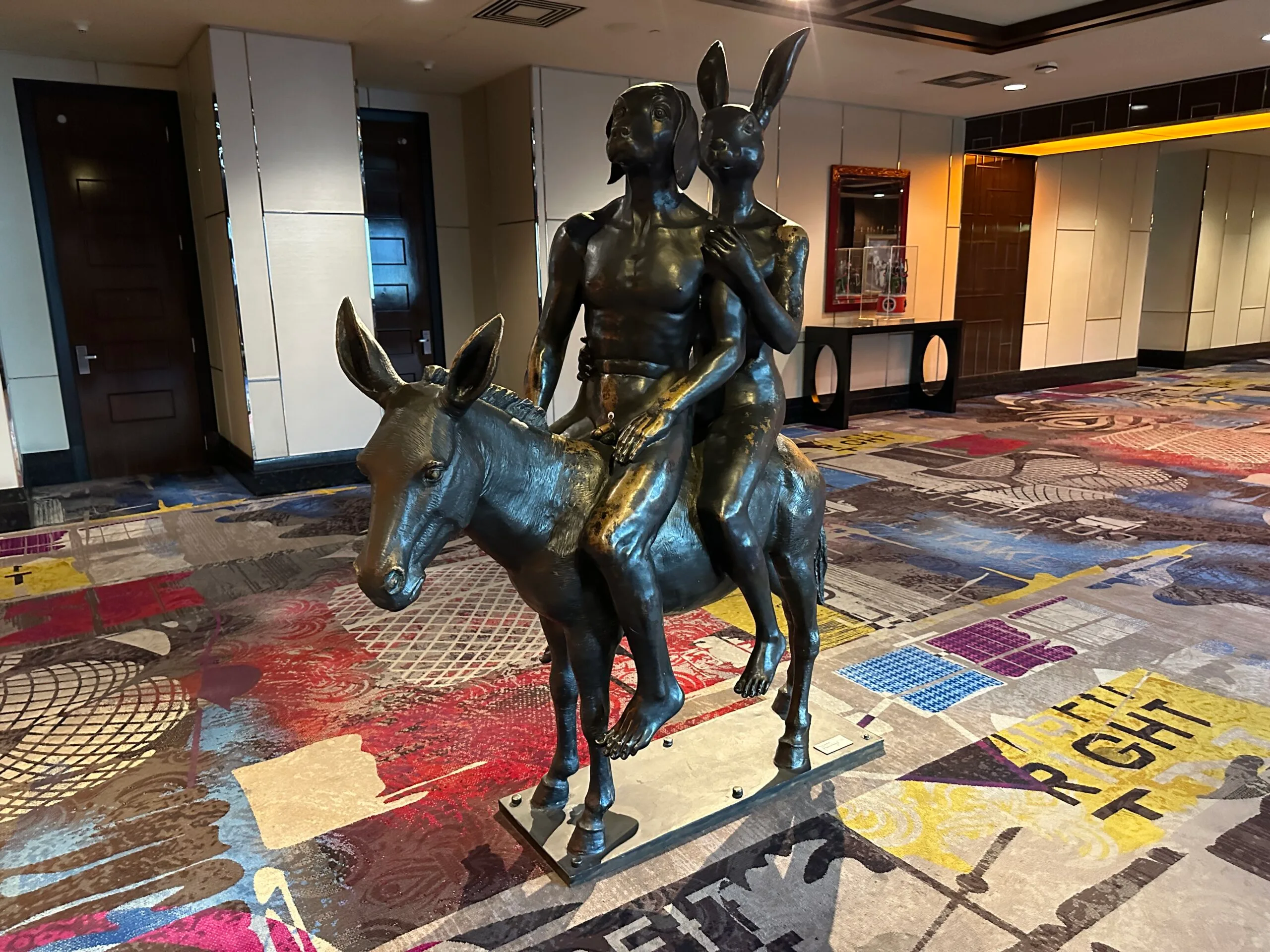 A bronze statue depicting a human-like dog and rabbit riding on a donkey.