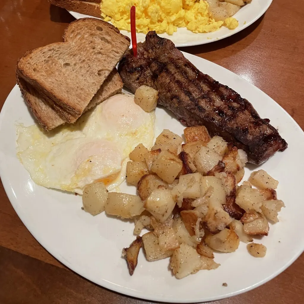 Steak, Eggs over easy, toast, and breakfast potatoes on a plate