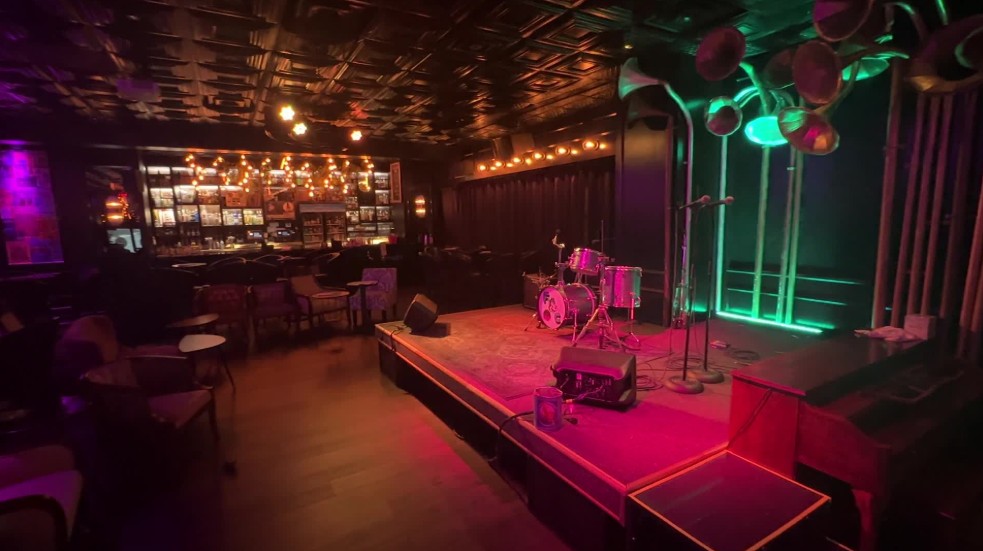 The stage at Fat Cat, with the bar illuminated in the background. 