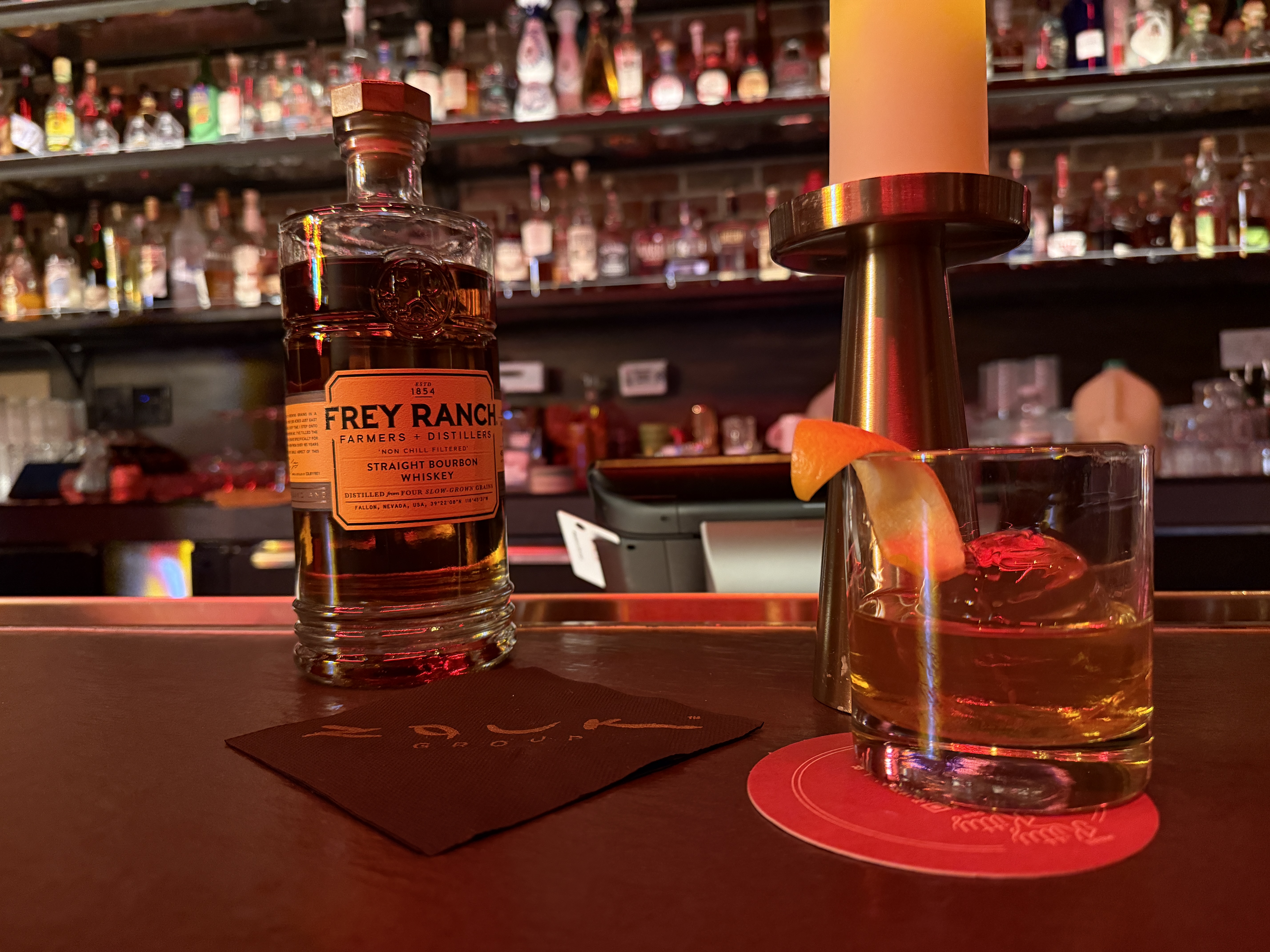 A bottle of bourbon next to a cocktail glass.