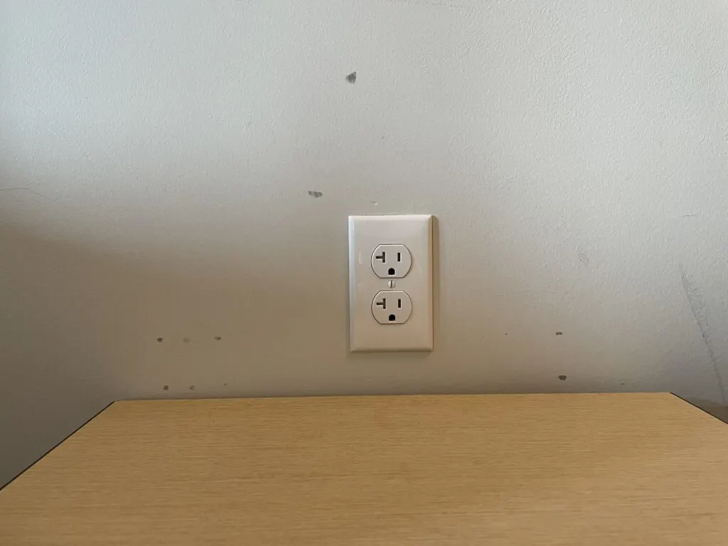 Scuffs on the wall surrounding a wall outlet.