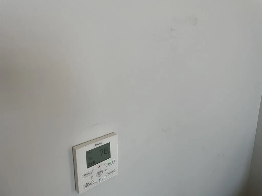 Scuffs on the wall surrounding a thermostat