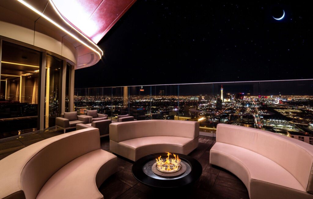 A firepit in Legacy Club's outdoor seating area with a view of the Strip to the south at night. 