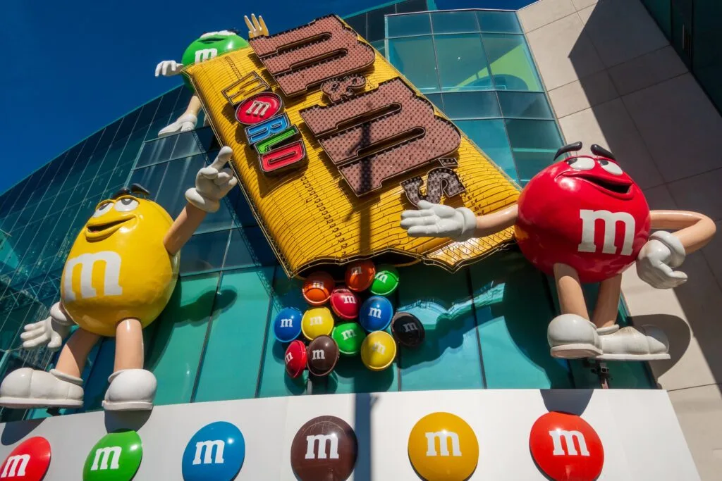Exterior of M&M World with two giant M&M characters posing on either side of a large bag of peanut M&Ms. 